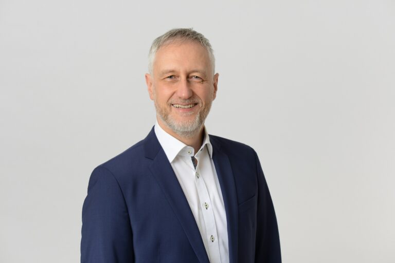 Dr. Stephan Ruppert lächelnd vor hellem Hintergrund